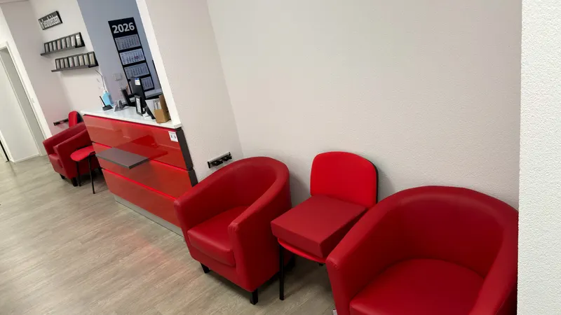 Wartebereich mit roten Sesseln neben dem Empfang